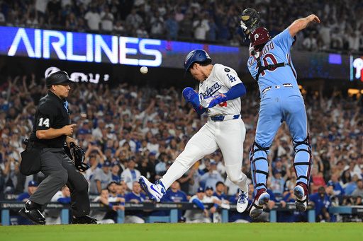 Los Angeles Dodgers' Hyeseong Kim, center, scores the game-winning run past Philadelphia Phillies catcher J.T. Realmuto (10) on a ground ball by Andy Pages and a throwing error by Phillies pitcher Orion Kerkering during the eleventh inning in Game 4 of baseball's National League Division Series Thursday, Oct. 9, 2025, in Los Angeles. (AP Photo/Mark J. Terrill) Los Angeles Dodgers' Hyeseong Kim, center, scores the game-winning run past Philadelphia Phillies catcher J.T. Realmuto (10) on a ground ball by Andy Pages and a throwing error by Phillies pitcher Orion Kerkering during the eleventh inning in Game 4 of baseball's National League Division Series Thursday, Oct. 9, 2025, in Los Angeles. (AP Photo/Mark J. Terrill)