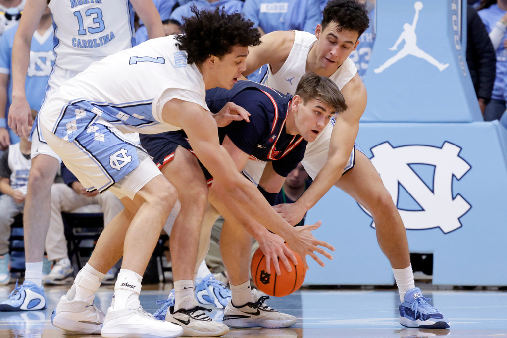 North Carolina forward Zayden High (1) and guard Luka Bogavac, top, defend against Radford guard Brennan Rigsby, bottom, during the first half of an NCAA college basketball game, Tuesday, Nov. 11, 2025, in Chapel Hill, N.C. (AP Photo/Chris Seward)
