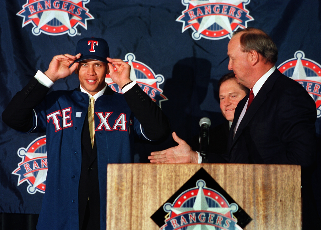Texas Rangers new short stop Alex Rodriguez, left, tries on the team's ball cap after being introduced to the Dallas/Fort Worth, Texas, media, Dec. 12, 2003, by team owner Tom Hicks, right, after Rodriguez signed a record $252 Million contract on Monday. (Brad Loper/The Dallas Morning News via AP)