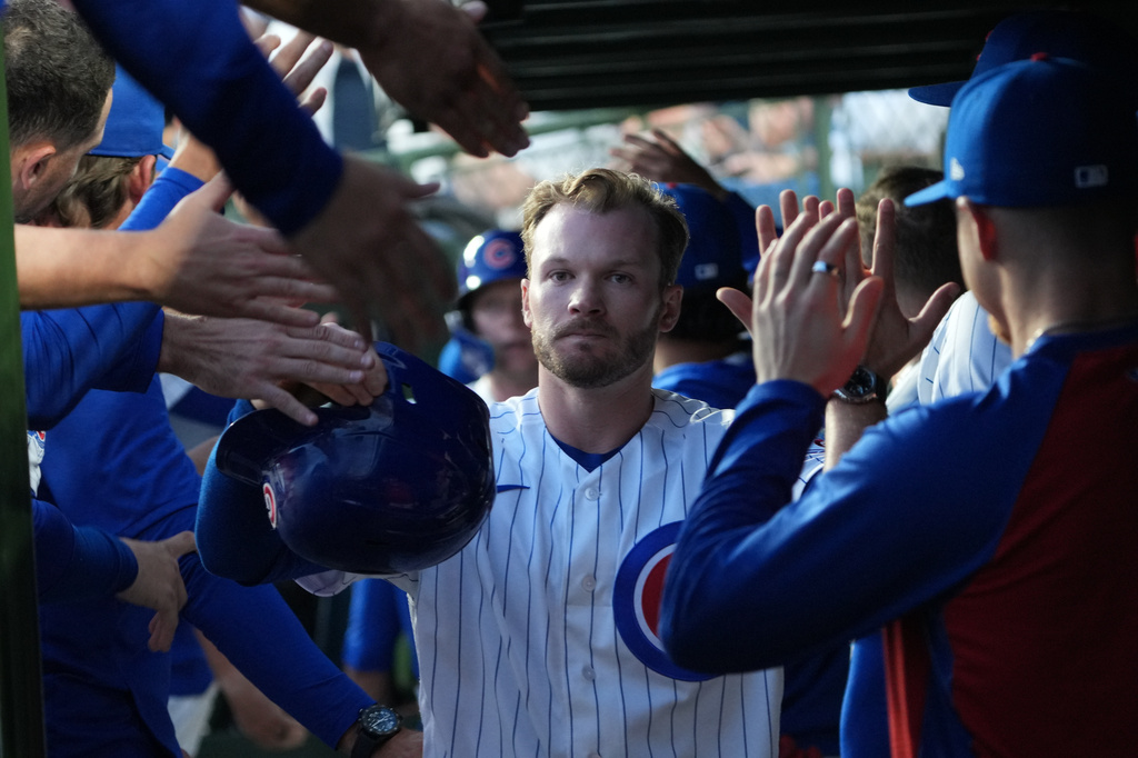 Chicago Cubs' Ian Happ is greeted in the dugout after scoring against the Los Angeles Angels during the first inning of a baseball game Monday, March 30, 2026, in Chicago. (AP Photo/David Banks)