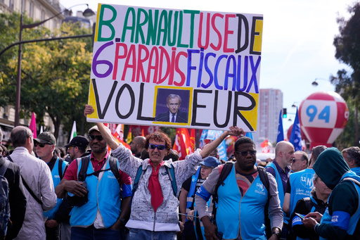 A demonstrator displays a poster of luxury group LVMH CEO Bernard Arnault reading" B Arnault uses 6 tax havens , thief" during a new round of strikes and protests against the caretaker government and cost-cutting Thursday, Oct. 2, 2025 in Paris. (AP Photo/Michel Euler) A demonstrator displays a poster of luxury group LVMH CEO Bernard Arnault reading" B Arnault uses 6 tax havens , thief" during a new round of strikes and protests against the caretaker government and cost-cutting Thursday, Oct. 2, 2025 in Paris. (AP Photo/Michel Euler)