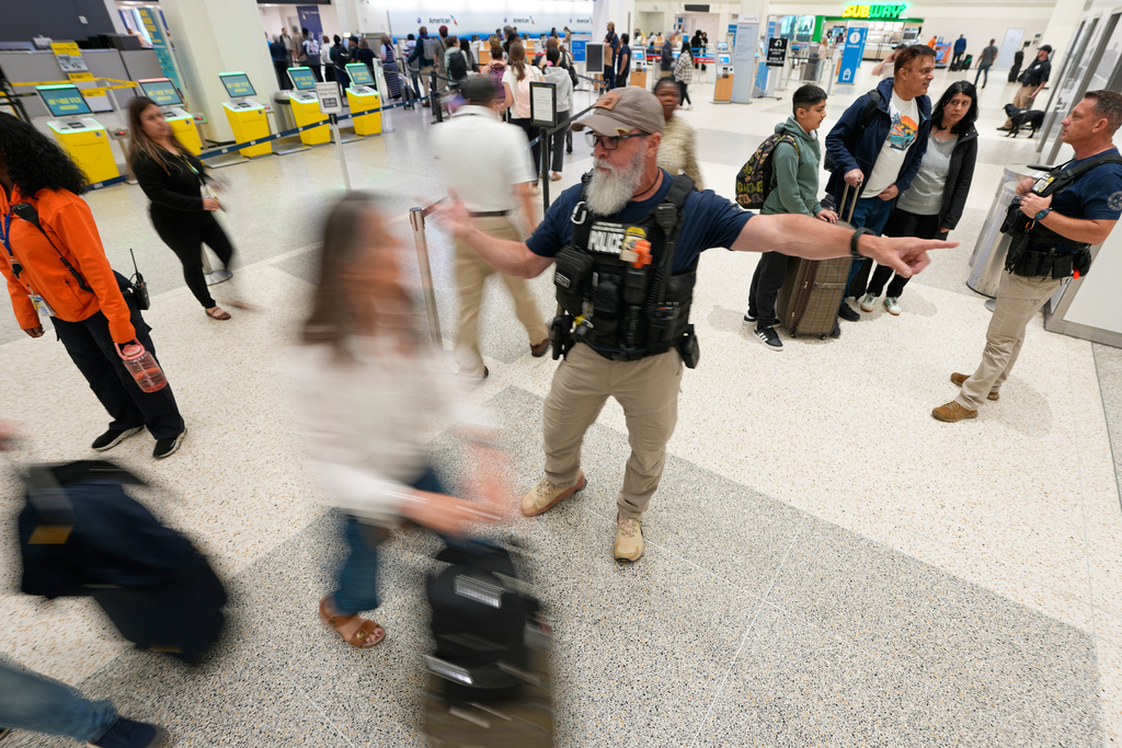 A Federal immigration officer directs passengers through a security checkpoint line at George Bush Intercontinental Airport Wednesday, March 25, 2026, in Houston. (AP Photo/David J. Phillip)
