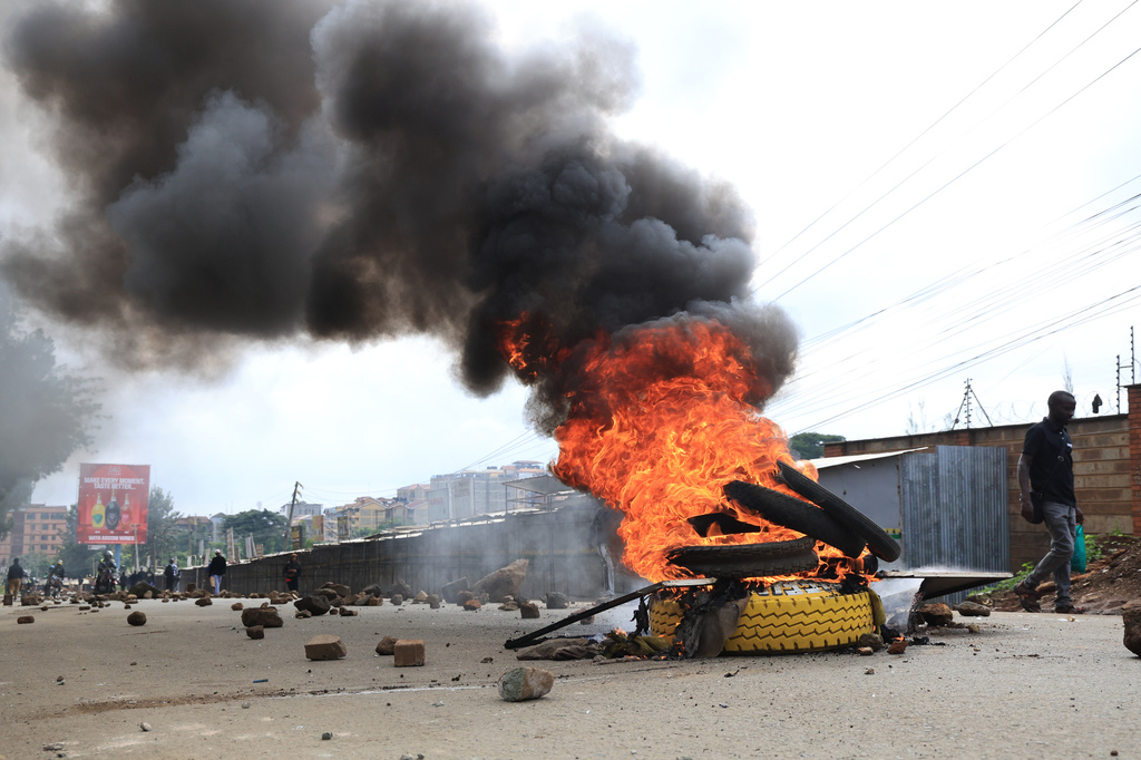 A man walks past burning tyres during a public transport strike over fuel prices in Nairobi, Kenya, Monday, May 18, 2026. (AP Photo/Andrew Kasuku)