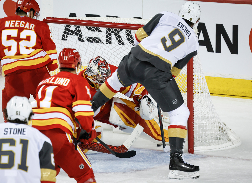 Vegas Golden Knights' Jack Eichel, right, scores on Calgary Flames goalie Dustin Wolf during third period NHL hockey action in Calgary on Tuesday, Oct. 14, 2025. (Jeff McIntosh/The Canadian Press via AP)