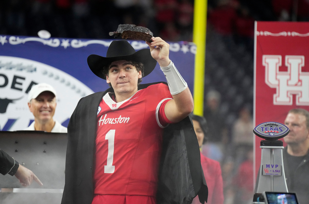 Houston quarterback Conner Weigman (1) wears a cowboy hat as part of his MVP trophy as he prepares to take a bite of BBQ after the Kinder's Texas Bowl NCAA football game, Saturday, Dec. 27, 2025, in Houston. (AP Photo/Karen Warren)
