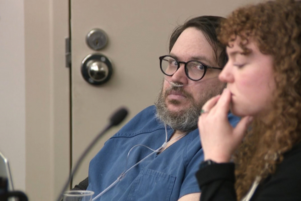 In this image captured from video, Nicholas Rossi, left, appears in a Salt Lake City court, Monday, Oct. 20, 2025, for his sentencing hearing on a rape conviction. To his right is MacKenzie Potter of the Salt Lake Legal Defender Association. (Fox 13/Pool Video via AP)