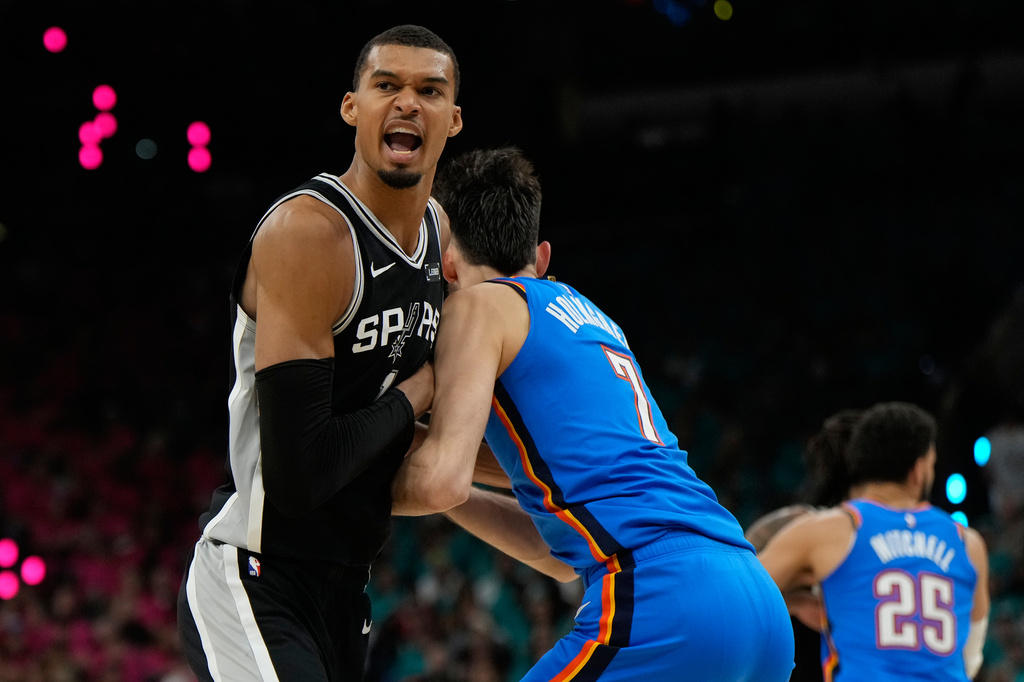 San Antonio Spurs forward Victor Wembanyama, left, reacts while defended by Oklahoma City Thunder center Chet Holmgren during the first half of Game 3 in the Western Conference finals NBA basketball playoffs series Friday, May 22, 2026, in San Antonio. (AP Photo/Ashley Landis)