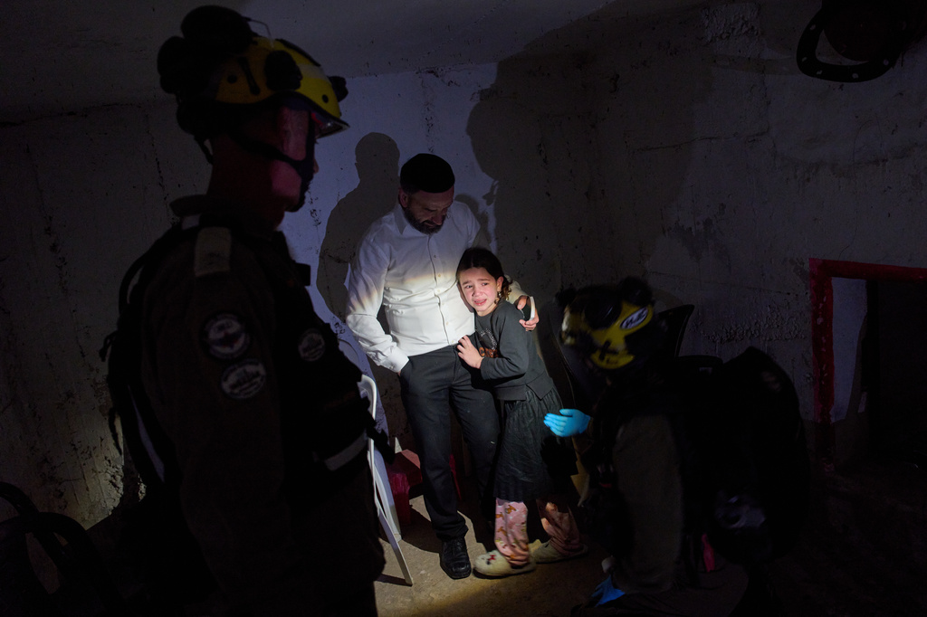 A young girl is comforted by her father and Israeli soldiers as they take cover in a bomb shelter during air raid sirens warning of incoming Iranian missile strikes in Bnei Brak, Israel, Wednesday, April 1, 2026. (AP Photo/Oded Balilty)
