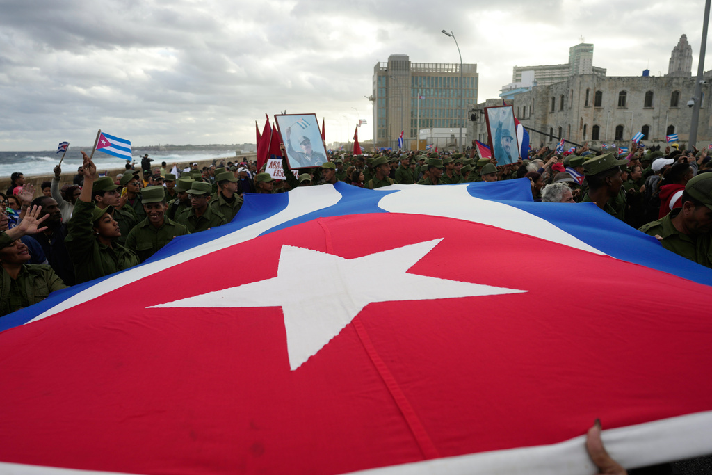 People carry a Cuban flag during a government-organized rally protesting the killing of Cuban officers in Venezuela while U.S. forces captured Venezuelan President Nicolas Maduro and his wife, in Havana, Cuba, Friday, Jan. 16, 2026. (AP Photo/Ramon Espinosa)