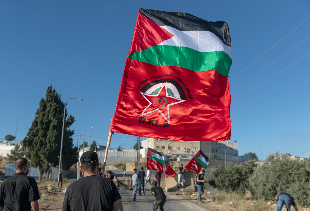 FILE - Palestinian protesters fly Palestinian flags and flags of the Democratic Front for the Liberation of Palestine, DFLP, during clashes with Israeli soldiers at the entrance the Jewish settlement of Beit El, background near the West Bank city of Ramallah, Tuesday, June. 15, 2021. (AP Photo/Nasser Nasser, file)