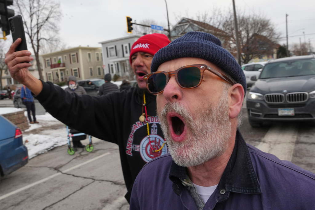People shout toward Border Patrol agents making an arrest, Sunday, Jan. 11, 2026, in Minneapolis. (AP Photo/Adam Gray)