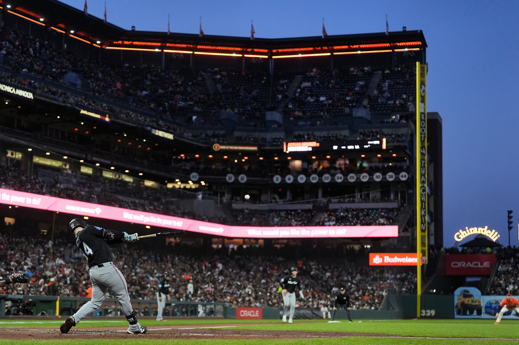 Miami Marlins' Liam Hicks, bottom left, hits a sacrifice fly that scored Kyle Stowers during the third inning of a baseball game against the San Francisco Giants in San Francisco, Friday, April 24, 2026. (AP Photo/Jeff Chiu)