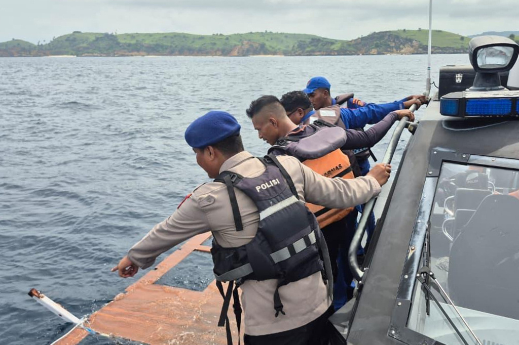 In this photo released by the Indonesian National Search and Rescue Agency (BASARNAS) on Saturday, Dec. 27, 2025, rescuers examine a debris believed to be from a tour boat that sank, near Padar Island within Komodo National Park, Indonesia. (BASARNAS via AP)
