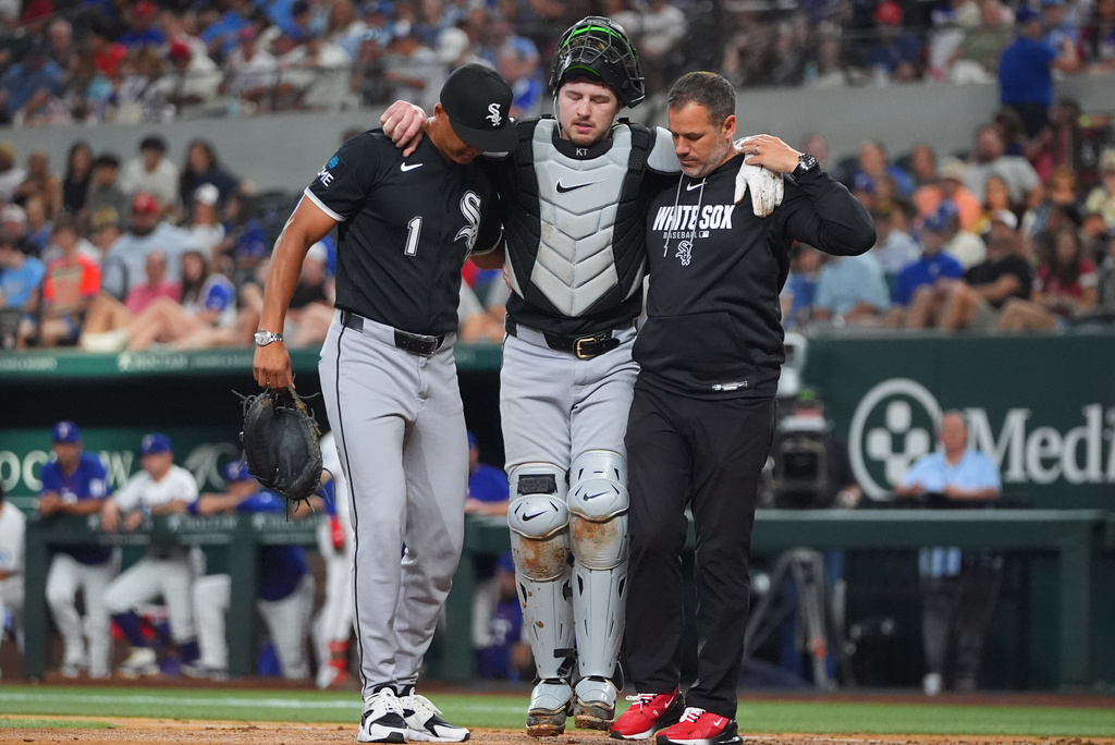 Chicago White Sox catcher Kyle Teel, center, his helped off the field by manager Will Venable (1) and trainer Brett Walker, right, during the second inning of a baseball game against the Texas Rangers, Monday, July 20, 2026, in Arlington, Texas. (AP Photo/LM Otero)