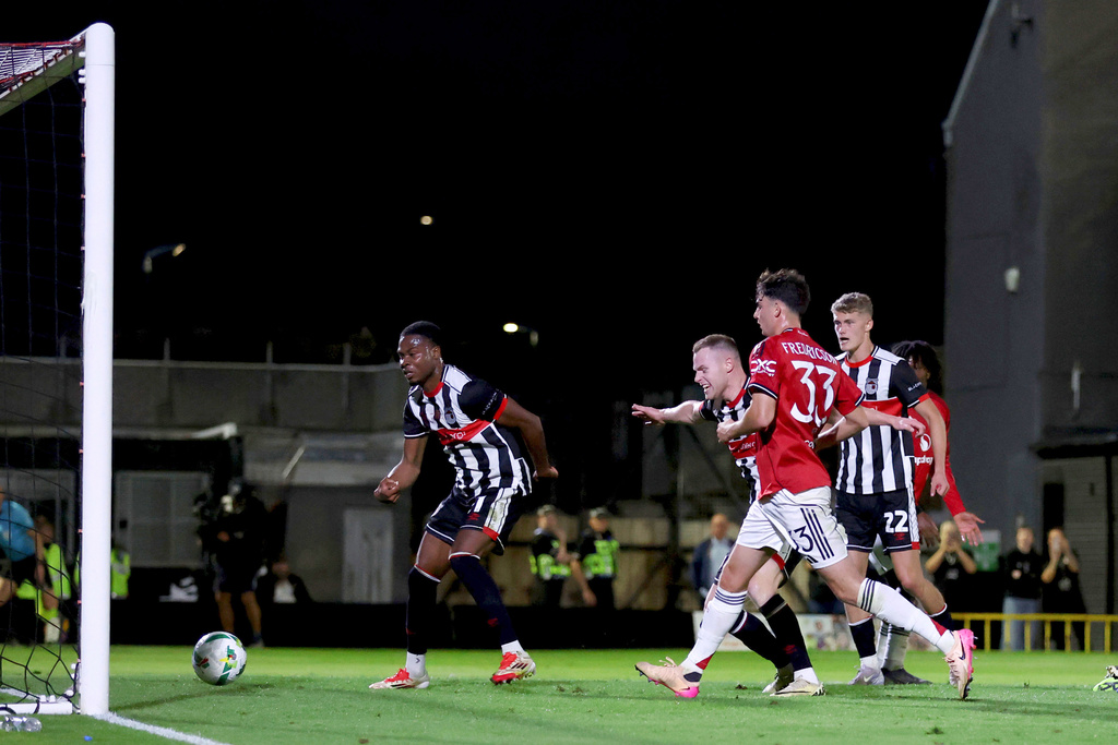 Grimsby Town's Tyrell Warren, left, scoring their side's second goal during an English League Cup second round soccer match against Manchester United, Wednesday, Aug. 27, 2025, at Hill Blundell Park in Grimsby, England. (Nigel French/PA via AP)