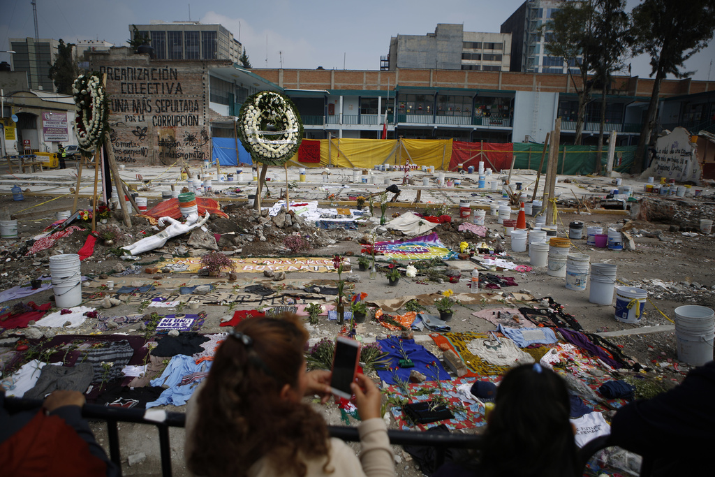 FILE - Clothing, cloth, and flowers are arranged in a memorial that includes the messages in Spanish: "Our lives matter" and "Our bodies are not trash," at the site of a textile factory that collapsed in an earthquake in Mexico City, Sept. 25, 2017. (AP Photo/Rebecca Blackwell, File)