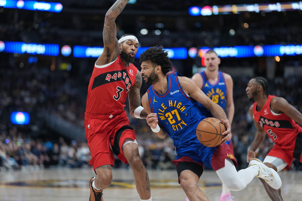 Denver Nuggets guard Jamal Murray, right, drives past Toronto Raptors forward Brandon Ingram in the first half of an NBA basketball game Friday, March 20, 2026, in Denver. (AP Photo/David Zalubowski)