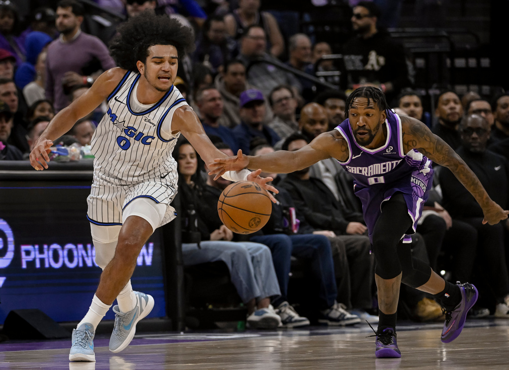 Orlando Magic guard Anthony Black, left, and Sacramento Kings guard Malik Monk, right, chase the ball during the first half of an NBA basketball game in Sacramento, Calif., Thursday, Feb. 19, 2026. (AP Photo/Randall Benton)
