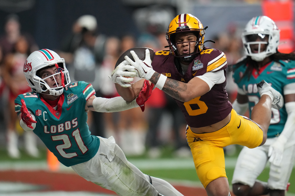 Minnesota defensive lineman Steven Curtis, right, scores a touchdown in overtime in front of New Mexico safety Austin Brawley (21) during a Rate Bowl NCAA college football game, Friday, Dec. 26, 2025, in Phoenix. (AP Photo/Rick Scuteri)