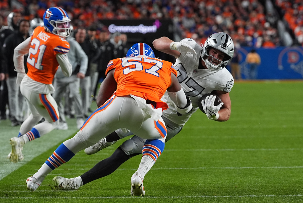 Las Vegas Raiders tight end Michael Mayer (87) is stopped by Denver Broncos linebacker Dre Greenlaw (57) during the first half of an NFL football game Thursday, Nov. 6, 2025, in Denver. (AP Photo/David Zalubowski)