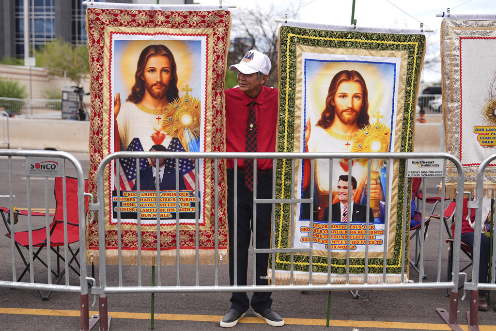 Paul Vu and other church members from Houston gather outside of a memorial for conservative activist Charlie Kirk, Sunday, Sept. 21, 2025, at State Farm Stadium in Glendale, Ariz. (AP Photo/Jae C. Hong)