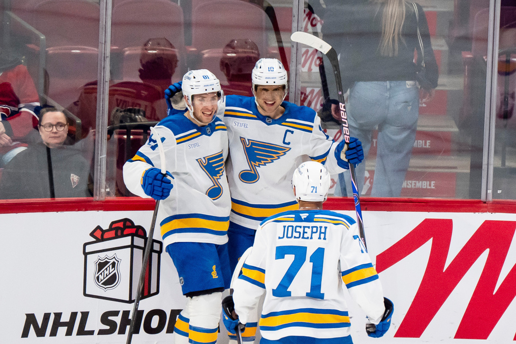 St. Louis Blues' Dylan Holloway (81) celebrates after his goal with teammates Brayden Schenn (10) and Mathieu Joseph (71) during second-period NHL hockey game action against the Montreal Canadiens in Montreal, Sunday, Dec. 7, 2025. (Christopher Katsarov/The Canadian Press via AP)