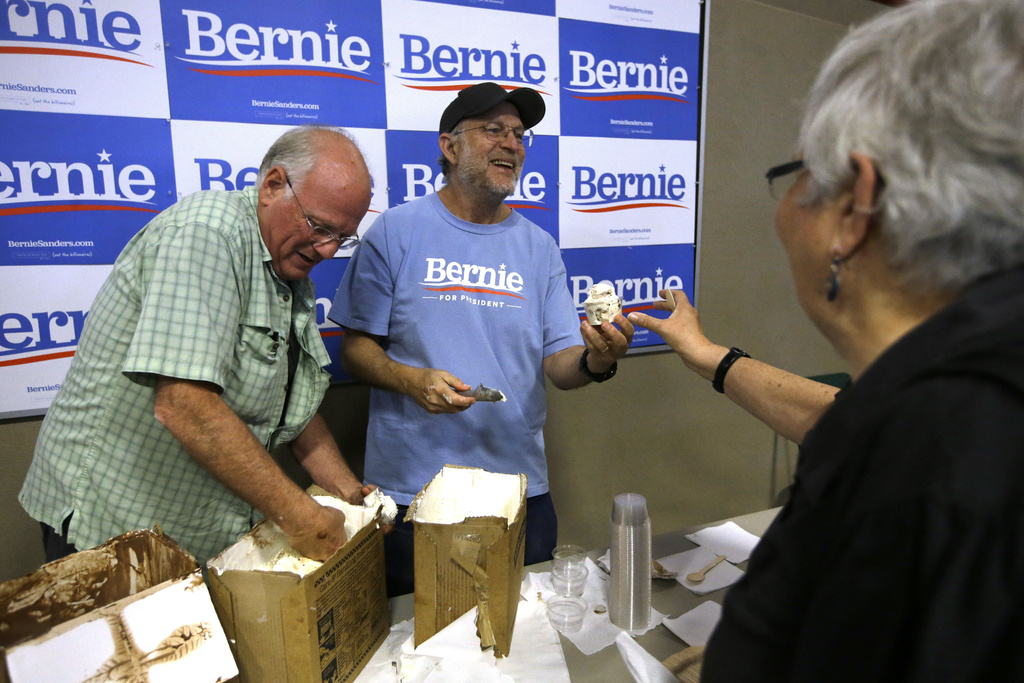 FILE - Ben & Jerry's co-founder Ben Cohen, left, and fellow co-founder Jerry Greenfield, center, scoop ice cream before a campaign event for Sen. Bernie Sanders, I-Vt., not shown, Sept. 1, 2019, in Raymond, N.H. (AP Photo/Steven Senne, File)