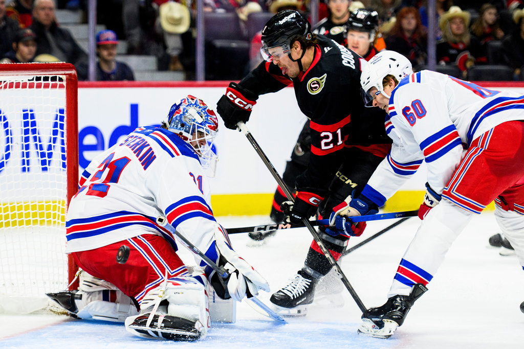 New York Rangers goaltender Igor Shesterkin, left, makes a save against Ottawa Senators' Nick Cousins (21) as Rangers' Scott Morrow (60) defends during second-period NHL hockey game action in Ottawa, Ontario, Thursday, Dec. 4, 2025. (Spencer Colby/The Canadian Press via AP)