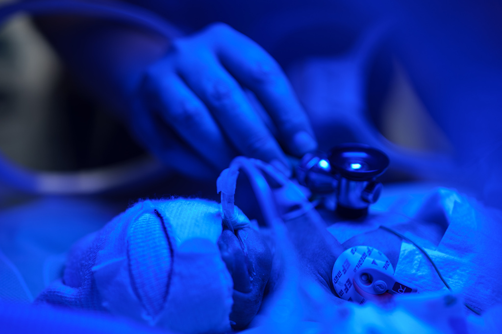 Dr. Andrii Lobanov listens to a premature baby's heartbeat with a stethoscope inside a temperature-controlled incubator at the regional perinatal center of Zaporizhzhia, Ukraine, Wednesday, May 6, 2026. (AP Photo/Evgeniy Maloletka)