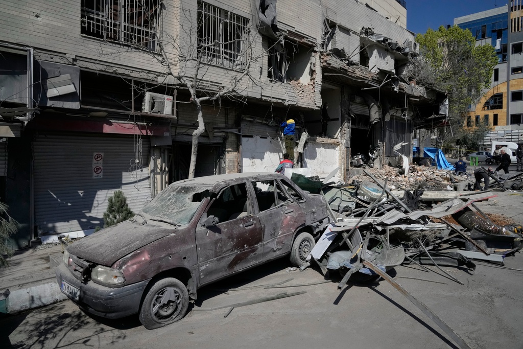Workers inspect a damaged building across the street from a police facility struck during the U.S.–Israeli military campaign in Tehran, Iran, Wednesday, March 4, 2026. (AP Photo/Vahid Salemi)