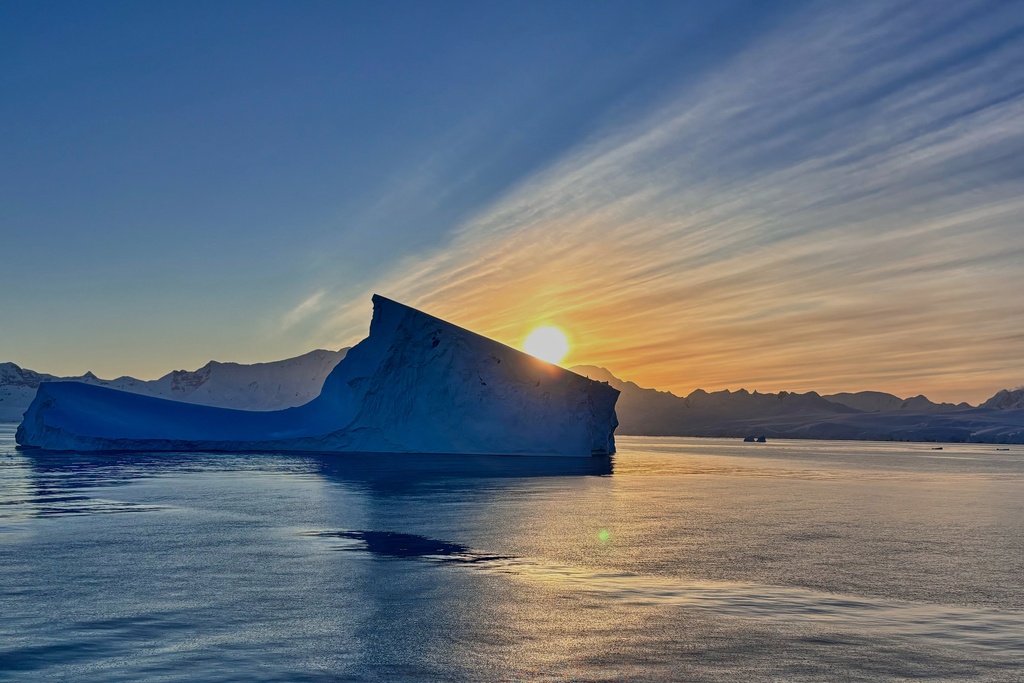 The sun sets near a iceberg in Antarctica, Friday, Nov. 21, 2025. (AP Photo/Mark Baker)