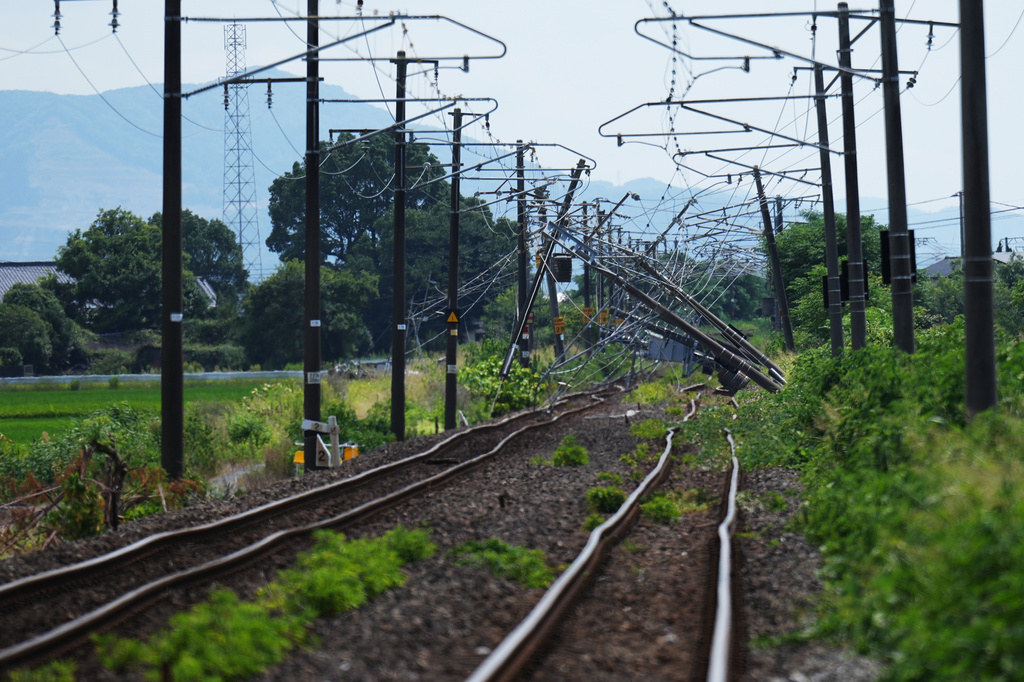 Electric poles are seen fallen over rail tracks in Hikawa, southern Japan, Thursday, July 30, 2026, two days after an earthquake hit the area. (AP Photo/Hiro Komae)