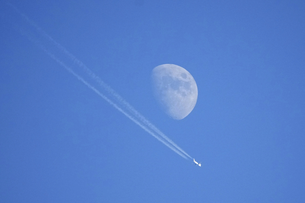 FILE - An airplane flies high in the sky with the moon in the background in Garmisch-Partenkirchen, Germany, Jan. 1, 2023. (AP Photo/Matthias Schrader, File)