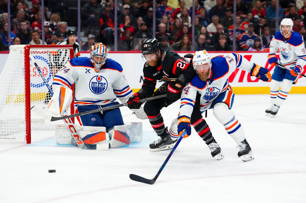 Edmonton Oilers' goaltender Stuart Skinner (74) keeps his eye on the puck as Edmonton Oilers' Mattias Ekholm (14) and Ottawa Senators' Claude Giroux (28) battle it out during second period NHL hockey action in Ottawa on Tuesday, Oct. 21, 2025. (Sean Kilpatrick/The Canadian Press via AP)
