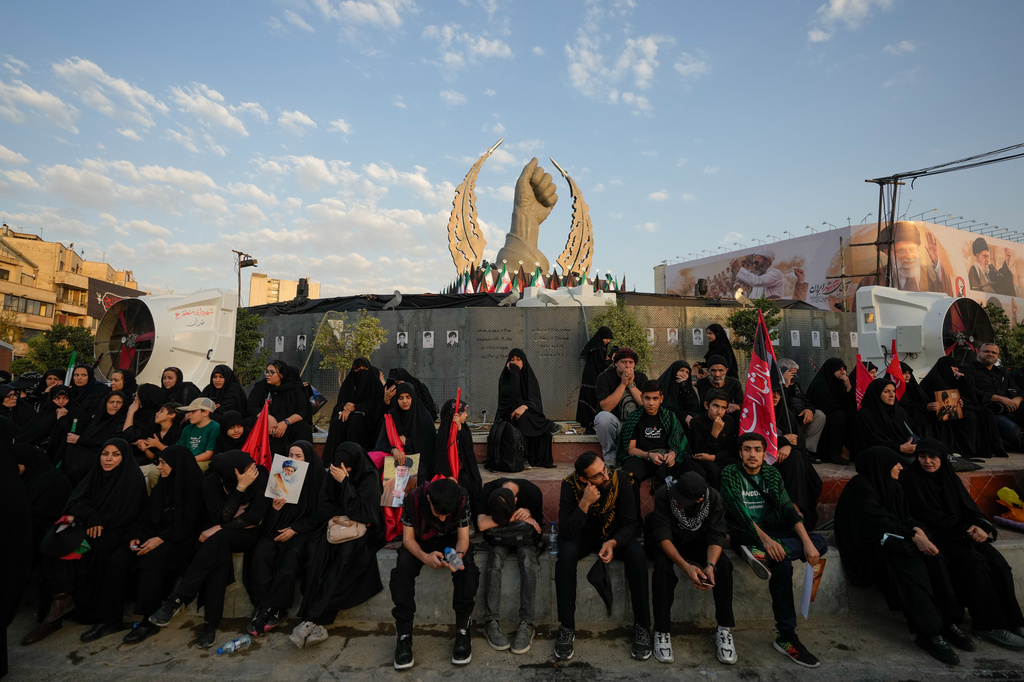 Mourners wait in Islamic Revolution Square for the funeral procession of the slain Iranian Supreme Leader Ayatollah Ali Khamenei beneath a monument depicting Khamenei's clenched fist in Tehran, Iran, Monday, July 6, 2026. (AP Photo/Vahid Salemi)