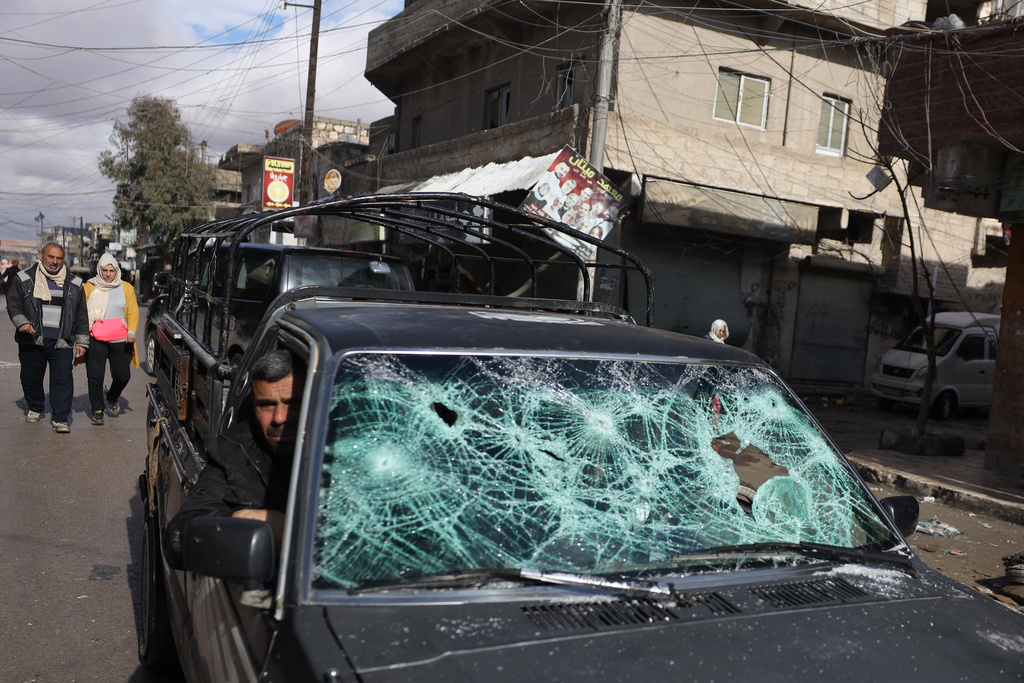 A man rides a damaged car, as displaced residents return to the Sheikh Maqsoud neighborhood after days of fighting between government forces and Kurdish fighters in the northern city of Aleppo, Syria, Tuesday, Jan. 13, 2026. (AP Photo/Omar Albam)