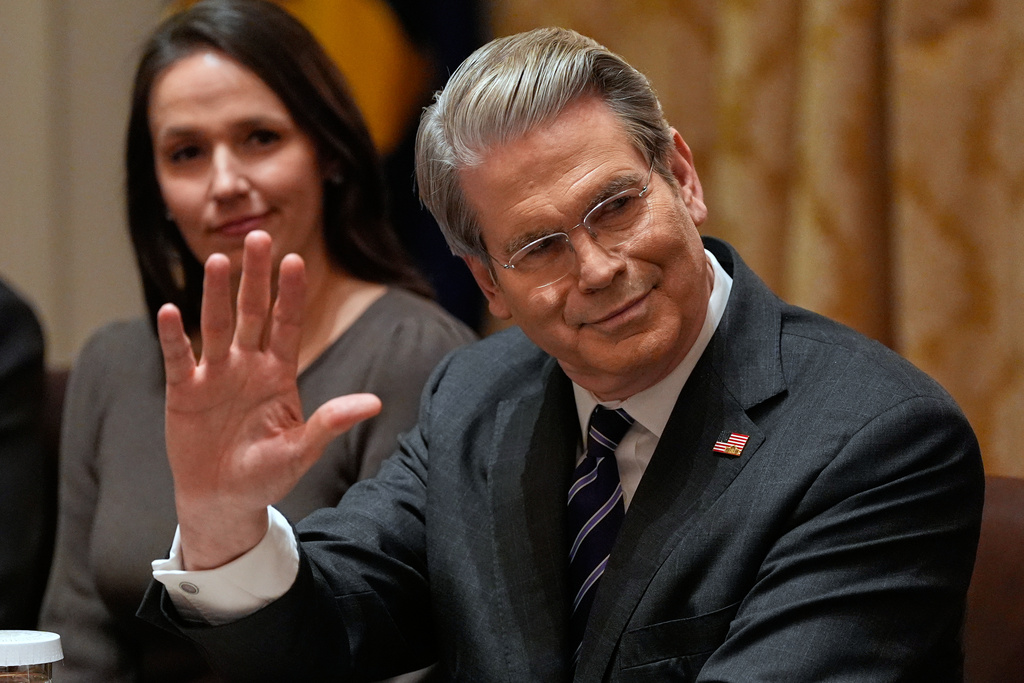 Treasury Secretary Scott Bessent waves during a roundtable meeting with President Donald Trump on farm subsidies in the Cabinet Room of the White House, Monday, Dec. 8, 2025, in Washington. (AP Photo/Alex Brandon)