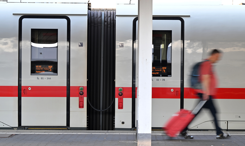 A passenger walks past an ICE train at Munich Central Station in Munich, Germany Wednesday, June 24, 2026, following the nationwide service disruption on the Deutsche Bahn network. (Peter Kneffel/dpa via AP)