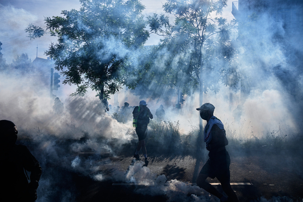 Protesters and others disperse amidst tear gas during a "No G7" demonstration in Geneva, Switzerland, Sunday, June 14, 2026, ahead of the G7 summit scheduled to take place June 15-17. (AP Photo/Laurent Cipriani)