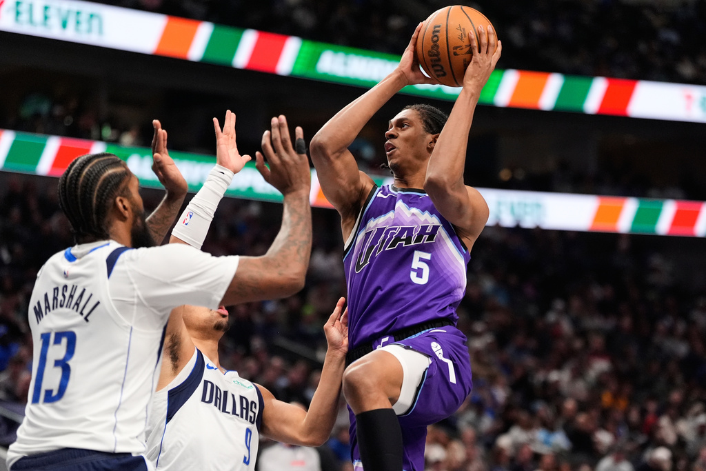 Utah Jazz forward Cody Williams (5) leaps to the basket to shoot as Dallas Mavericks' Naji Marshall (13) and Ryan Nembhard (9) defend in the first half of an NBA basketball game in Dallas, Saturday, Jan. 17, 2026. (AP Photo/Tony Gutierrez)