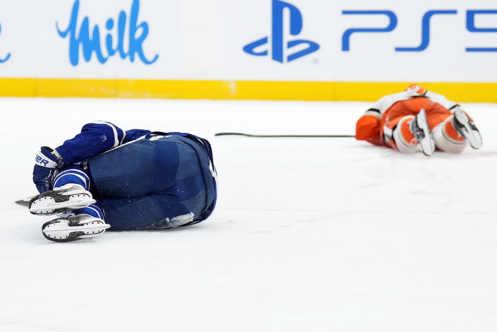 Toronto Maple Leafs Auston Matthews (34) and Anaheim Ducks Radko Gudas (7) lay on the ice after colliding during second period NHL hockey action in Toronto on Thursday, March 12, 2026. (Nathan Denette/The Canadian Press via AP)
