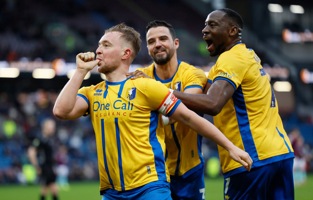 Mansfield Town's Louis Reed, left, celebrates scoring during the English FA Cup fourth round soccer match between Burnley and Mansfield Town in Burnley, England, Saturday Feb. 14, 2026. (Richard Sellers/PA via AP)