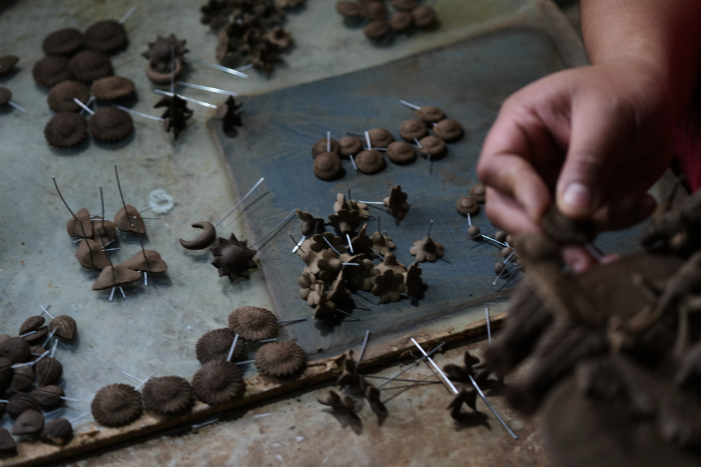 Mexican craftsman Luis Hernandez inserts small fragile clay figures into a tree of life sculpture at his atelier in Metepec, Mexico, Thursday, Oct. 9, 2025. (AP Photo/Fernando Llano)