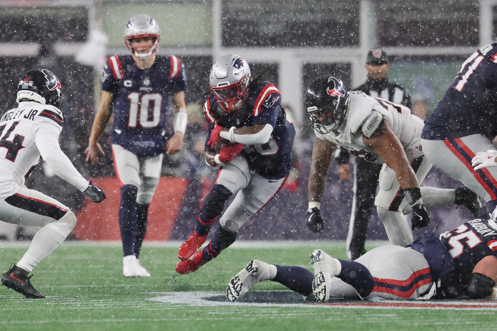 New England Patriots running back Rhamondre Stevenson, middle, runs against the Houston Texans during the second half of an NFL divisional playoff football game, Sunday, Jan. 18, 2026, in Foxborough, Mass. (AP Photo/Mark Stockwell)