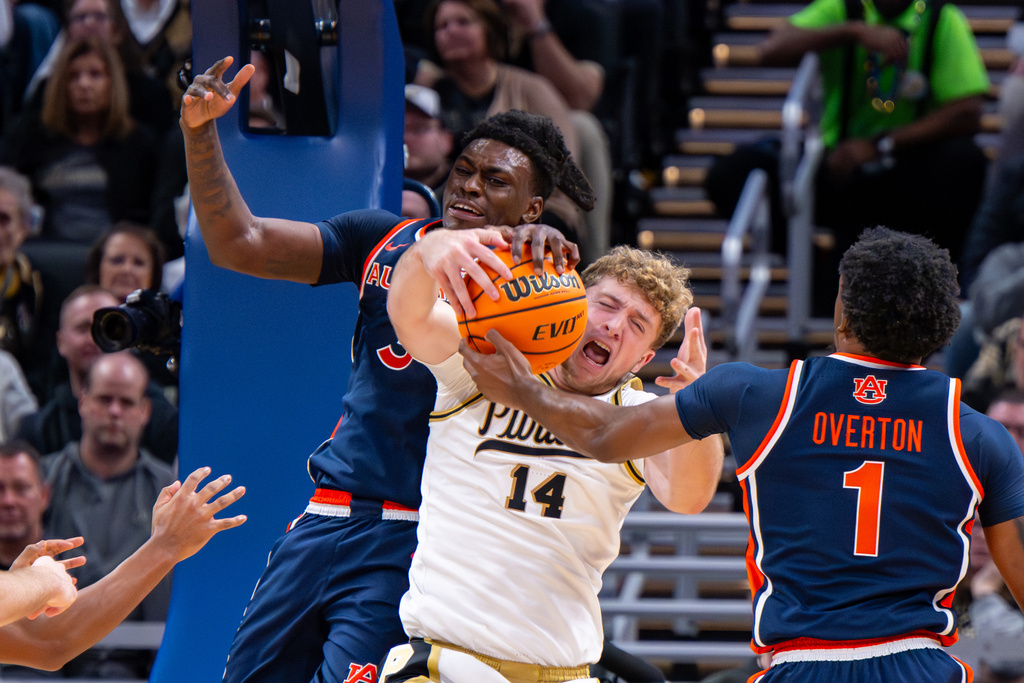 Purdue guard Jack Benter (14) reacts as he battles for a rebound with Auburn forward Keshawn Murphy, left, and guard Kevin Overton (1) during the first half of an NCAA college basketball game, Saturday, Dec. 20, 2025, in Indianapolis (AP Photo/Doug McSchooler)