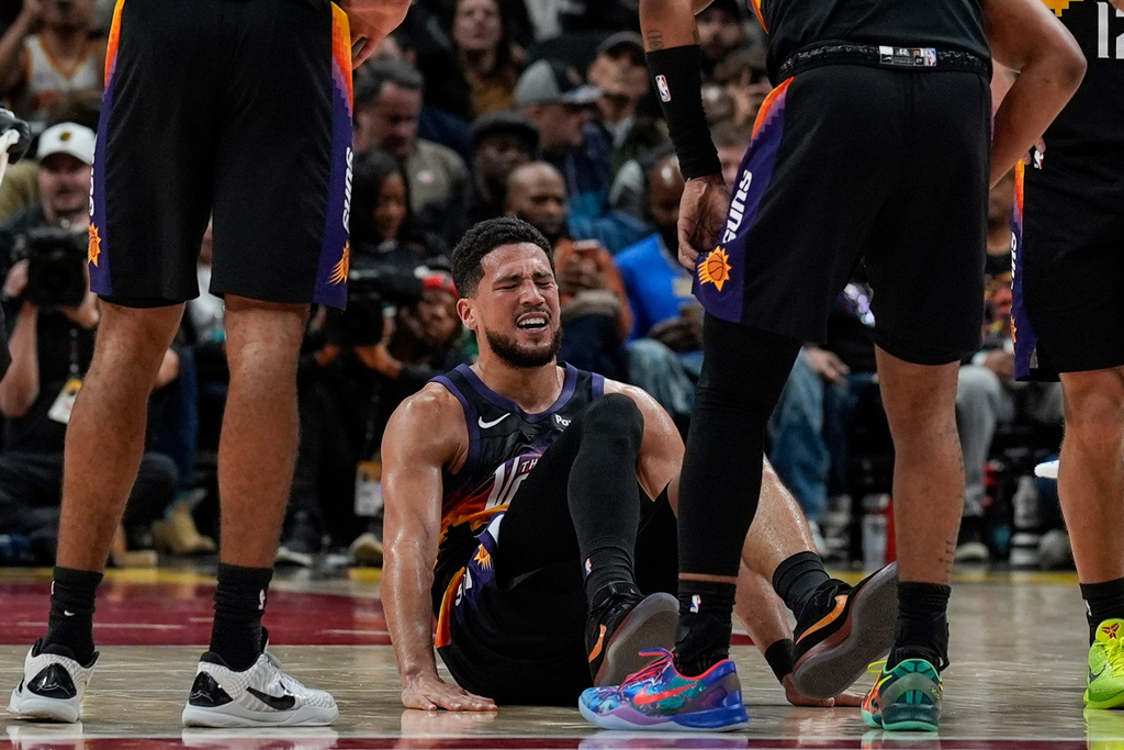 Phoenix Suns guard Devin Booker (1) winces in pain during the second half of an NBA basketball game against the Atlanta Hawks, Friday, Jan. 23, 2026, in Atlanta. (AP Photo/Mike Stewart)