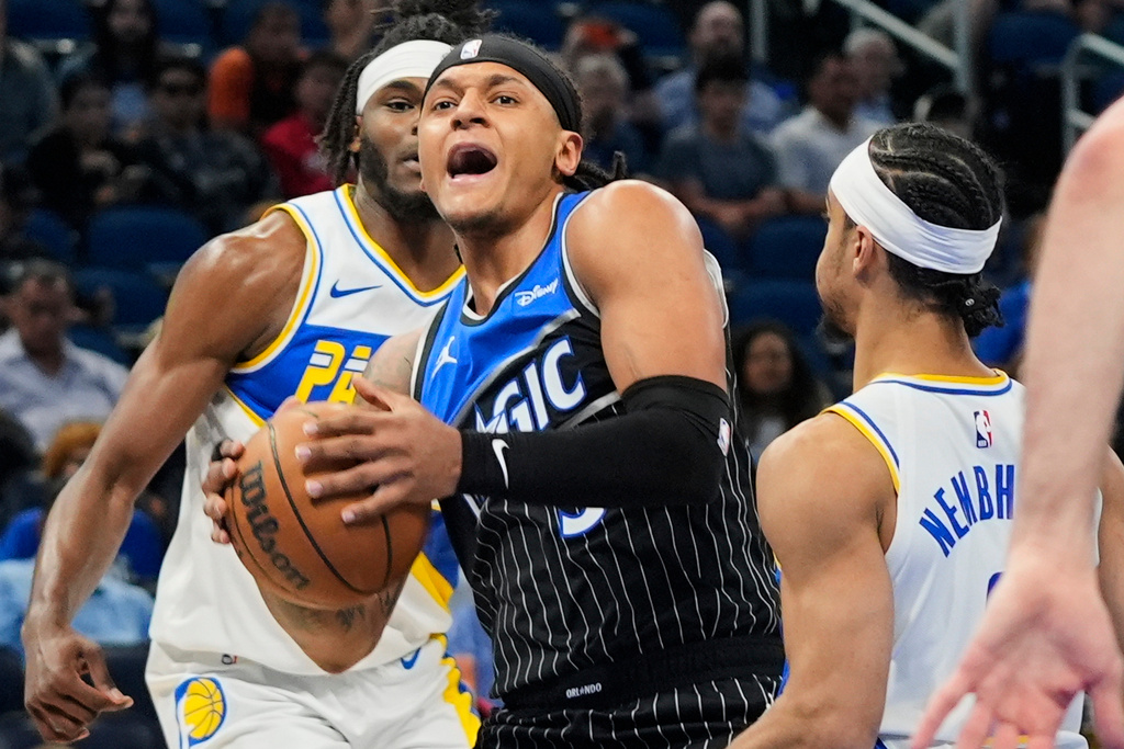 Orlando Magic forward Paolo Banchero, center, tries to move past Indiana Pacers forward Jarace Walker, back left, and guard Andrew Nembhard, right, during the first half of an NBA basketball game, Monday, March 23, 2026, in Orlando, Fla. (AP Photo/John Raoux)