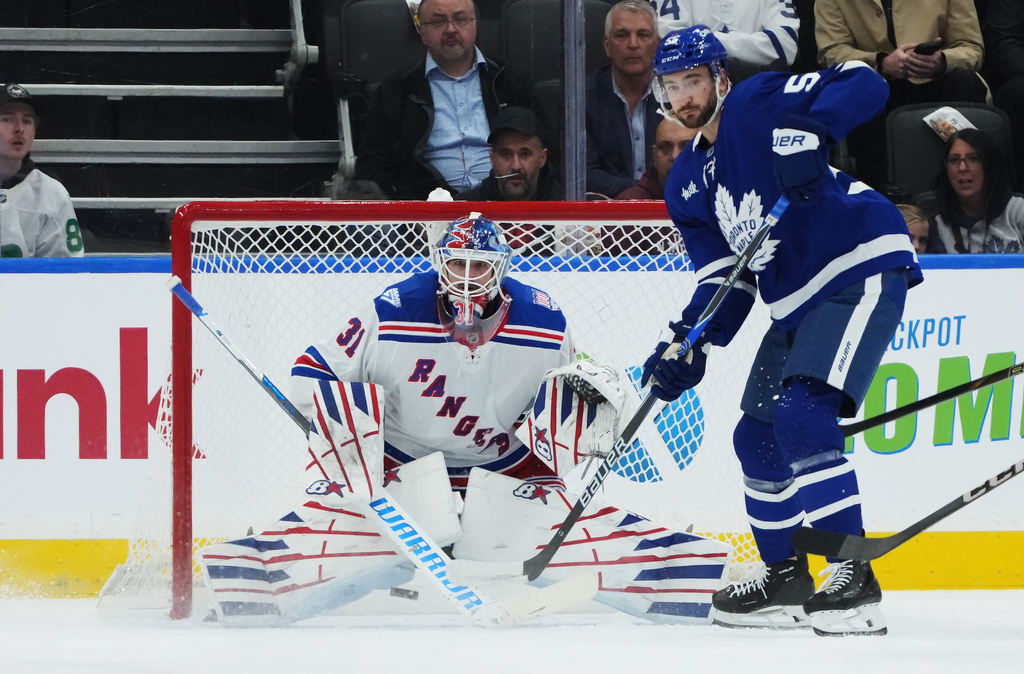New York Rangers goaltender Igor Shesterkin (31) and Toronto Maple Leafs' Nicolas Roy (55) keep their eyes on the puck during first period NHL hockey action in Toronto on Thursday, Oct. 16, 2025. (Nathan Denette/The Canadian Press via AP)