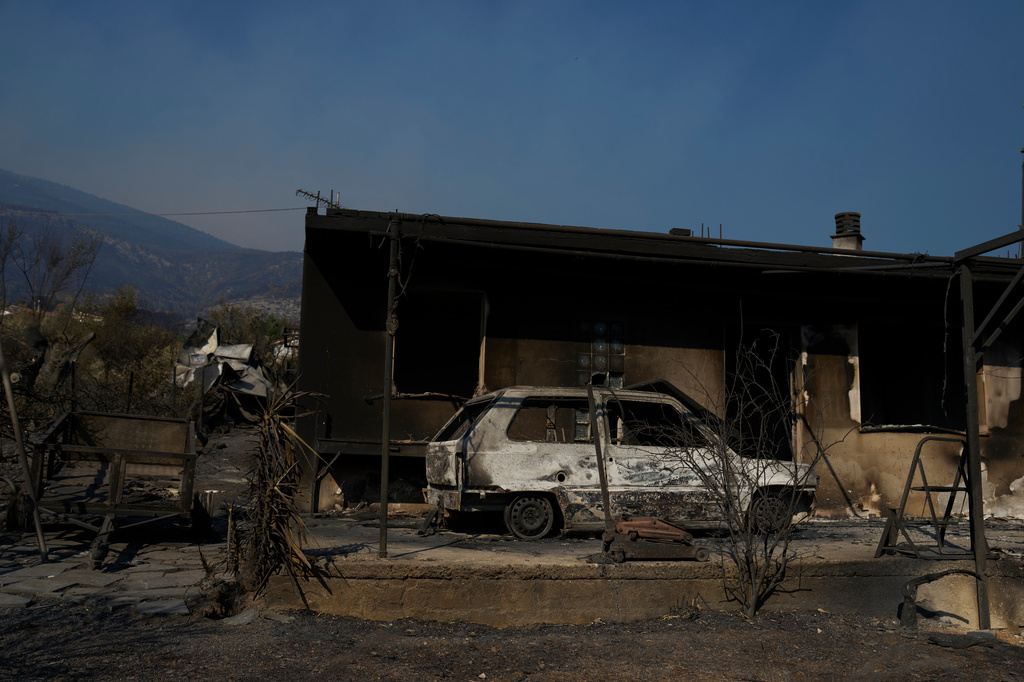A house and a car destroyed by a wildfire are seen in Porto Germeno, northwest of Athens, Greece, Monday, Aug. 3, 2026. (AP Photo/Petros Giannakouris)