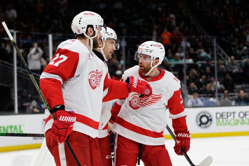 Detroit Red Wings left wing James van Riemsdyk (21), center, celebrates a goal with center Michael Rasmussen (27) and left wing J.T. Compher, right, against the Seattle Kraken during the second period of an NHL hockey game Saturday, Dec. 6, 2025, in Seattle. (AP Photo/John Froschauer)
